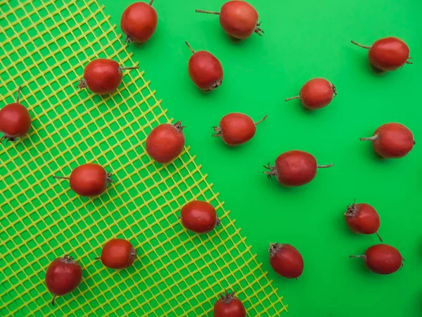 緑の背景にあるホーソンの赤い果実 背景の一部は黄色のプラスチック網で覆われています上からの眺め — ストック写真