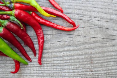 Taze kırmızı, yeşil acı biberler tahta bir yüzeyde solda yatıyor. Yukarıdan görünüm