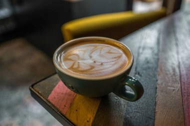 Renkli masada bir fincan kapuçino.