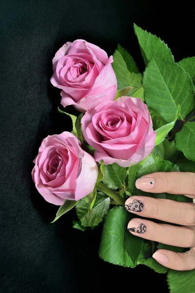 Mano femminile con manicure nail art e rose rosa — Foto Stock