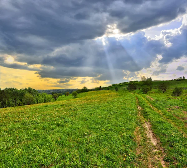 Sun beams through clouds floating over the meadow — Stock Photo, Image
