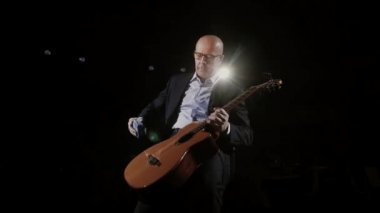 Takım elbiseli bir müzisyen sahne performansı için hazırlanıyor. O, akustik gitarı mavi mendille siliyor. Müzik okulu için yaratıcı bir kavram, müzik öğretmeni..