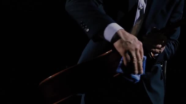 一位穿着西服的音乐家正在准备他的舞台表演 他正在用蓝手帕擦拭声吉他 音乐学校 音乐教师和教练的创意概念 — 图库视频影像