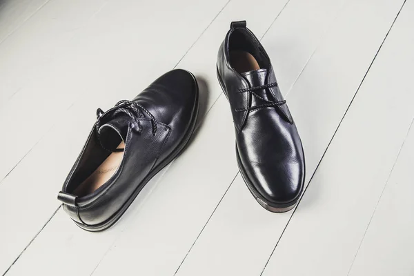 Chaussures en cuir noir pour hommes sur un tableau blanc — Photo