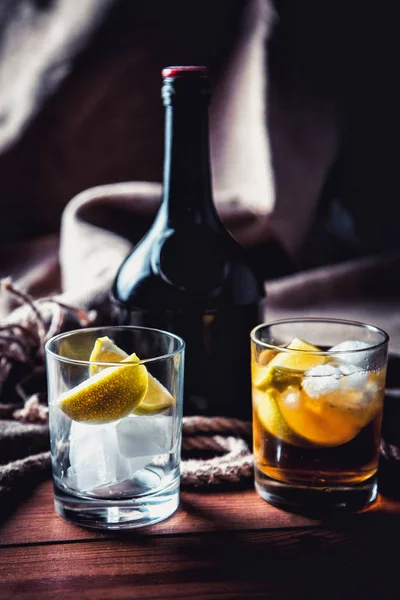 Eine Flasche Whiskey, Rum, Brandy, Limette auf einem hölzernen Hintergrund — Stockfoto