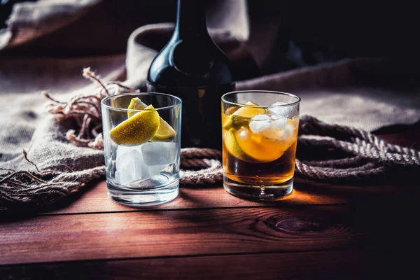 Eine Flasche Whiskey, Rum, Brandy, Limette auf einem hölzernen Hintergrund — Stockfoto