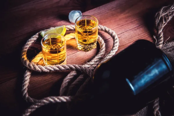 Бутылка виски, ром, бренди, лайм на деревянном фоне — стоковое фото