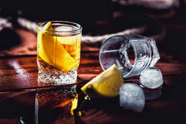 Eine Flasche Whiskey, Rum, Brandy, Limette auf einem hölzernen Hintergrund — Stockfoto