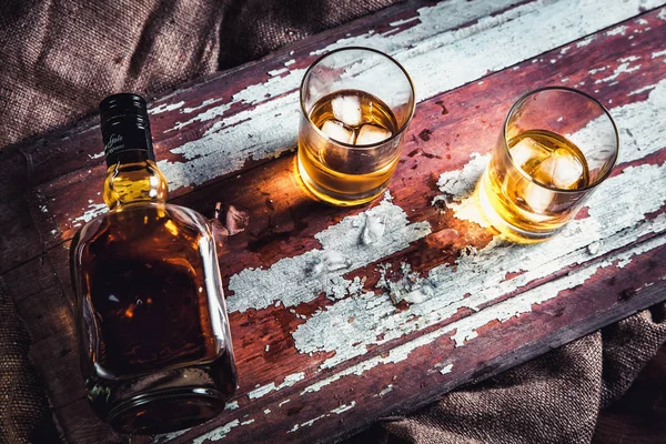 Bottiglia di whisky e vetro su uno sfondo vintage in legno — Foto Stock