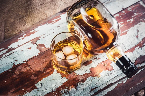 Whiskey bottle and glass on a wooden vintage background — Stock Photo, Image