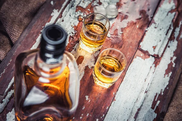 Bottiglia di whisky e vetro su uno sfondo vintage in legno — Foto Stock