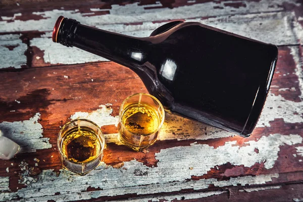 Whiskey bottle and glass on a wooden vintage background — Stock Photo, Image