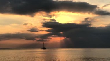 Koh Lanta, Tayland 'daki Long Beach' te gün batımında denizde yürüyen insanlar ve botlar.