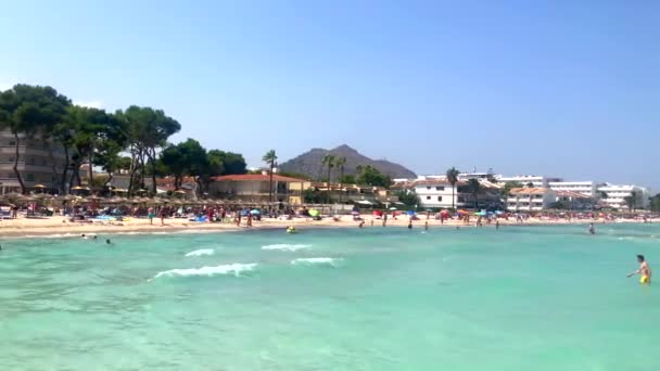 ALCUDIA, ESPAÑA, 15 de julio de 2019 - La gente disfruta de un día soleado en la playa de Alcudia, Mallorca, España — Vídeos de Stock