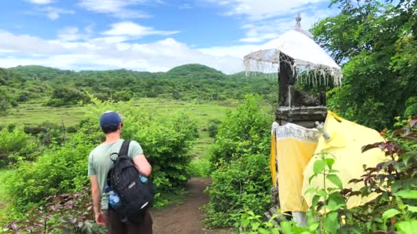 Spacer turysty będzie na wsi ze świątynią na wyspie Nusa Penida, Bali, Indonezja, 4k materiał wideo — Wideo stockowe