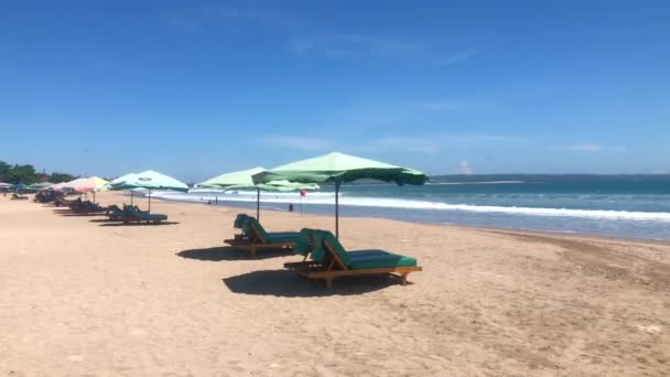 Wide sandy beach with many sunbeds and umbrellas Seminyak and Legian beach in Bali, Indonesia, 4k footage video — Stock Video