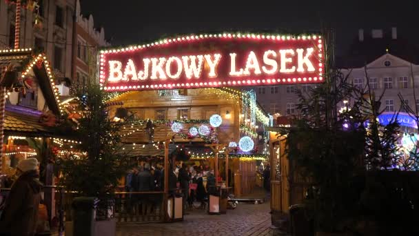 Familia feliz, gente divirtiéndose, comiendo en la Feria de Navidad por la noche. Decoración colorida de luces de Navidad, multitud en el casco antiguo de Wroclaw, Polonia 2018 — Vídeos de Stock