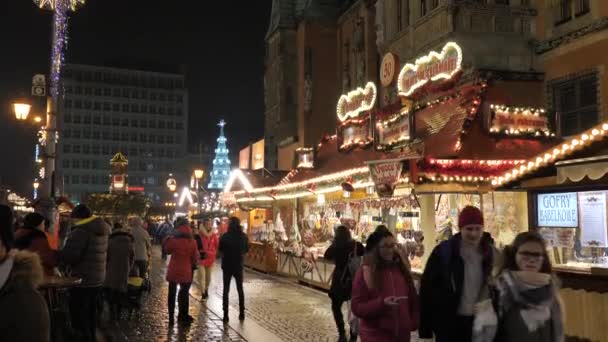 Familia feliz, gente divirtiéndose, comiendo en la Feria de Navidad por la noche. Decoración colorida de luces de Navidad, multitud en el casco antiguo de Wroclaw, Polonia 2018 — Vídeos de Stock