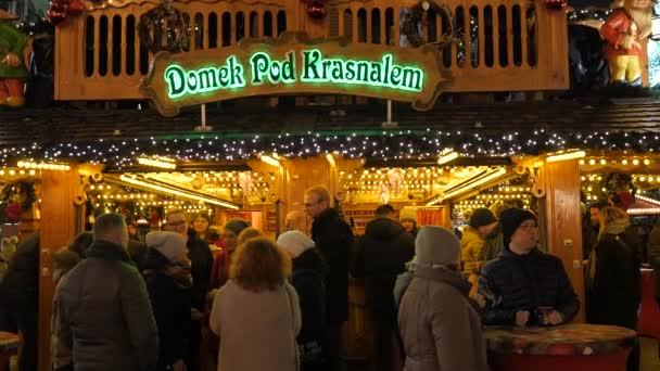 Familia feliz, gente divirtiéndose, comiendo en la Feria de Navidad por la noche. Decoración colorida de luces de Navidad, multitud en el casco antiguo de Wroclaw, Polonia 2018 — Vídeos de Stock