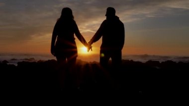 Slow motion couple joining hands together with sunlight in background. The suns rays shine through their fingers. Winner Love, Happiness and Friendship. Hands close up