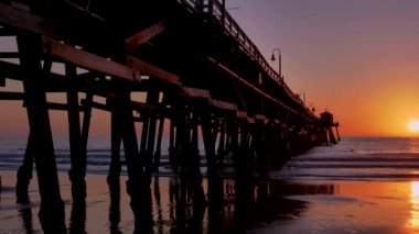 San Clementa California 'daki destansı ışık ve güneş ışınlarıyla turuncu pembe gün batımı ahşap iskele.