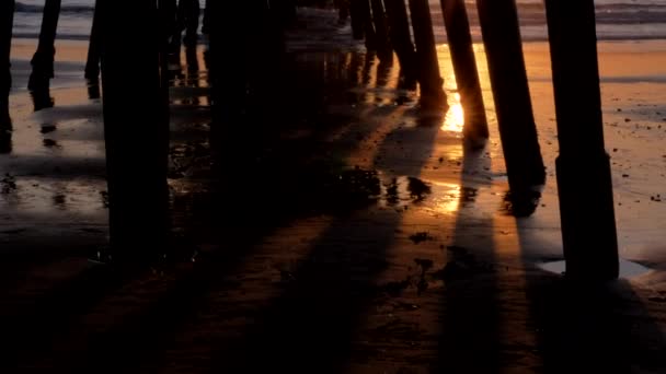 Slow tilt under the pier Scenic orange pink Sunset with epic rays of light and sun flare wooden pier in San Clementa California — Stock Video