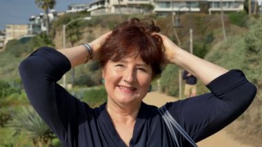 Güneşli yaz gününde mutlu bir kadın. Okyanus kıyısında bileklik takıyor. Seyahat Emeklilik Stili Kaliforniya Orange County San Clemente Konsepti