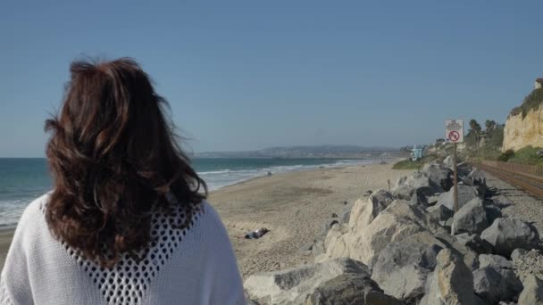 Senior kvinna på stranden tittar på havet med vackra landskap på sommardagen i Kalifornien san clemente calafia stranden. orange län livsstil — Stockvideo