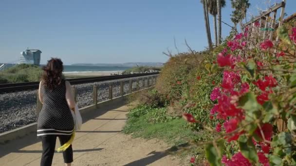 Kaliforniya San Clemente Calafia plajında yaz günü okyanusa yakın yaya yolunda güzel manzaralarla yürüyen aktif kıdemli bir kadın. Orange County yaşam tarzı — Stok video
