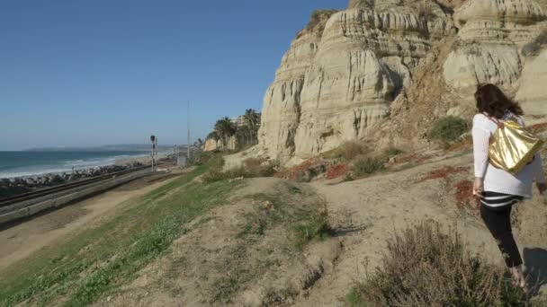 Donna anziana attiva a piedi sul sentiero pedonale vicino all'oceano con bellissimi paesaggi durante la giornata estiva in california san clemente spiaggia calafia. arancione contea stile di vita — Video Stock