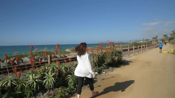 Active Senior femeie de mers pe jos la traseu pietonal aproape de ocean, cu peisaje frumoase în ziua de vară în California san clemente calafia plaja. stil de viață portocaliu județ — Videoclip de stoc