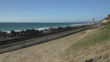 Kaliforniya San Clemente Calafia plajında yaz günü okyanusa yakın yaya yolunda güzel manzaralarla yürüyen aktif kıdemli bir kadın. Orange County yaşam tarzı