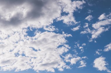 Güzel açık beyaz ve gri bulutlar mavi gökyüzüne karşı. Güneş arka plandaki ışıkla gökyüzünü aydınlatıyor..