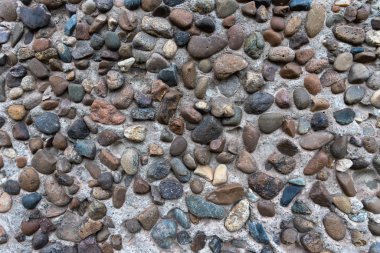 Beton alçı, bir sürü pürüzsüz nehir taşıyla birleşmiş. Dekoratif duvar.