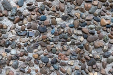 Beton alçı, bir sürü pürüzsüz nehir taşıyla birleşmiş. Dekoratif duvar.