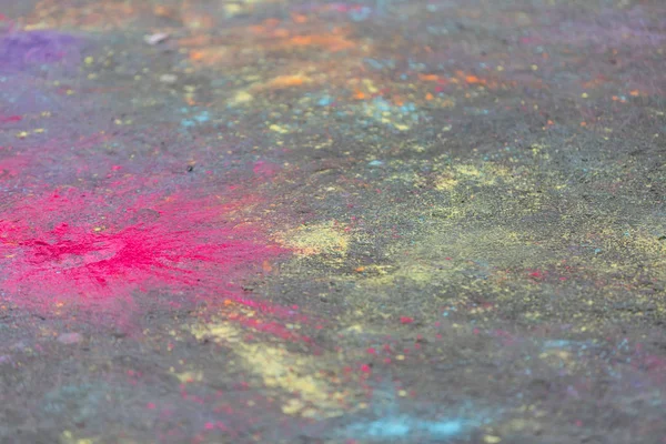Colored powder paints scattered on the asphalt during the Holi festival.