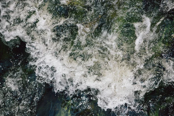 The rapid flow of water with white waves and air bubbles. Top view of a stream of fast flowing water.