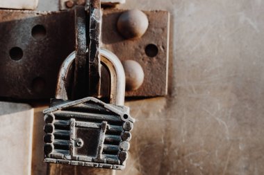 Kulübe şeklinde asma kilit kapalı kapının menteşelerinde asılı duruyor. Metal kapılar.