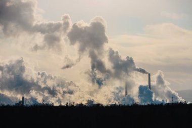 Fabrika bacaları atmosferi yoğun dumanla kirletir..