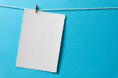 Mavi arka planda küçük mandalları olan boş kartpostalları işaretle.