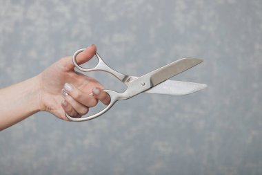Eski bir makas. Bir elde nadir bir makas. Kadın eli makası tutuyor. Gri arkaplan.