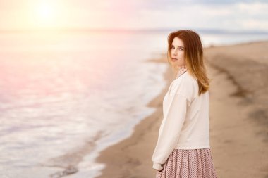 Genç ve güzel bir kız sahilde yürüyor ve arkasına bakıyor..