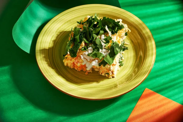 Yeşil kağıttan bir tabakta ev yapımı balık salatasını düşünün. Sert gölgeler ve parlak ışık ışınlarıyla.