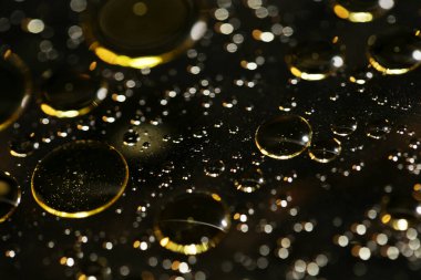 Su siyah zemin üzerinde Bokeh fi ile altın yağ kabarcıkları makro