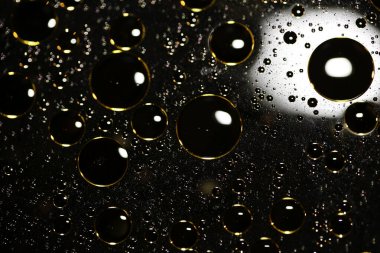 Su siyah zemin üzerinde Bokeh fi ile altın yağ kabarcıkları makro