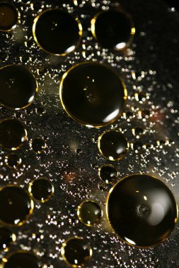 Su siyah zemin üzerinde Bokeh fi ile altın yağ kabarcıkları makro