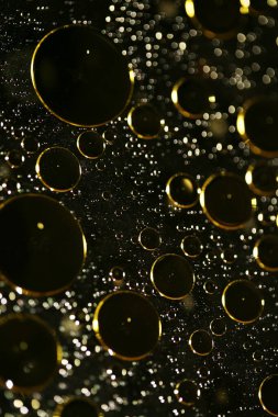 Su siyah zemin üzerinde Bokeh fi ile altın yağ kabarcıkları makro