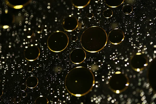 Su siyah zemin üzerinde Bokeh fi ile altın yağ kabarcıkları makro