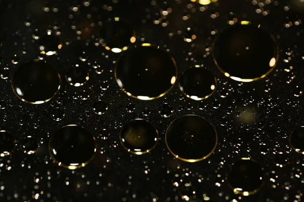 Su siyah zemin üzerinde Bokeh fi ile altın yağ kabarcıkları makro
