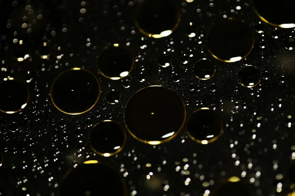 Su siyah zemin üzerinde Bokeh fi ile altın yağ kabarcıkları makro